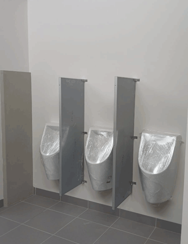 Urinales con paneles divisores en baño comercial moderno, espacio funcional karäna