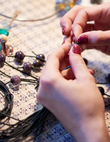 manos poniendo piedras sobre un hilo para realizar una pulsera