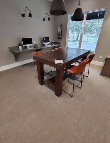 Picture of an office with two computer monitor and a table with four red chairs