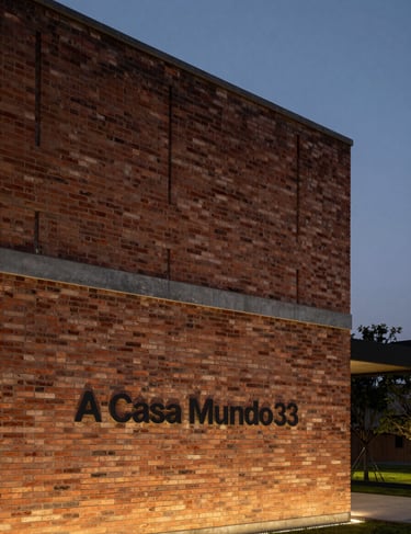 Architectural photography of 'A Casa Mundo', brick facade textures, storm gray accents, minimalist framing, elegant dusk lighting.