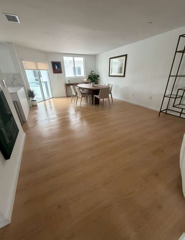 Modern open concept living area featuring light oak hardwood flooring and a minimalist dining set.