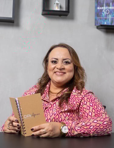 a woman in a pink shirt is holding a notebook and smiling