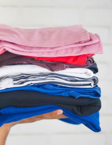 Hand holding a neatly folded stack of clean clothes .
