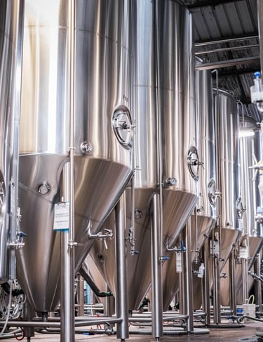 a bunch of metal tanks in a brewery