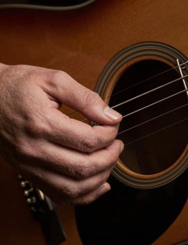 Detailed close-up of guitar strings vibrating as they are plucked, sharp focus on the metallic strings against a dark espresso brown background, North American / US.