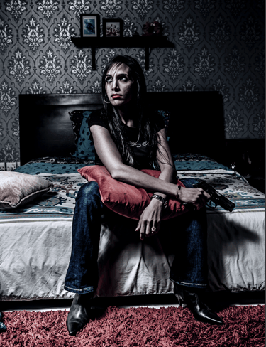 Cinematic portrait of woman with a gun, dramatic lighting, moody bedroom, fine art conceptual photo