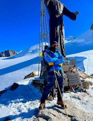 mais alhajri standing at a snowy mountain summit wearing blue climbing gear