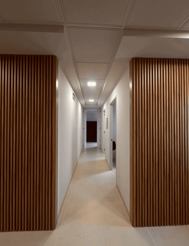 Corredor con muros blancos y listones de madera verticales con luz de techo | KARÄNA