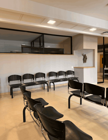 Sala de espera con sillas negras alineadas e iluminación cenital | KARÄNA