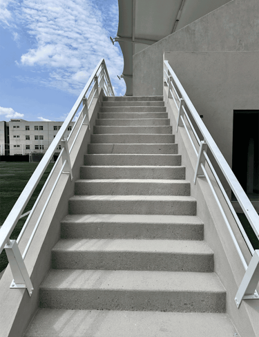 Escaleras con barandal blanco hacia gradas | KARÄNA