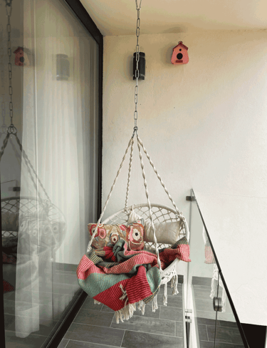 Balcón con columpio de cuerda, cojines decorativos y manta colorida, estilo bohemio | KARÄNA