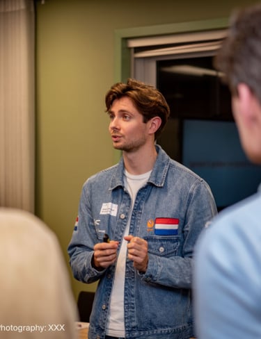A young professional man in a denim jacket leading a workshop discussion during a business seminar.