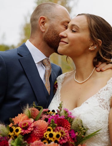 a bride and groom kissing in a field
