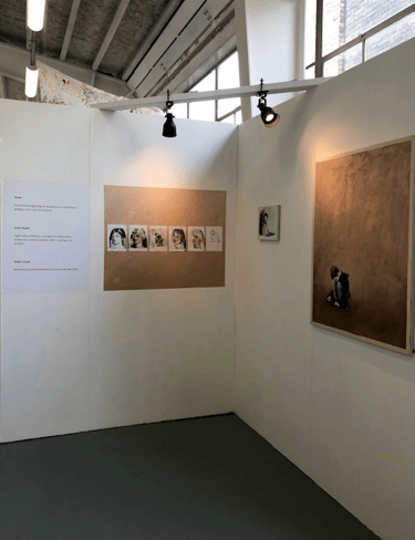 Art works in white wall gallery; 1 large and 1 small painting, 6 lino print portraits. Display text