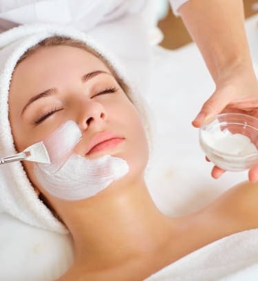 a woman getting a facial mask with a brush