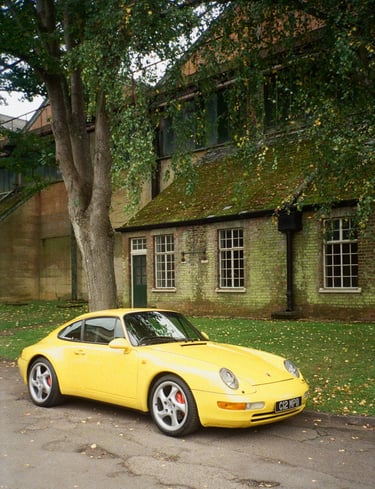 a yellow Porsche parked in front of a brick building