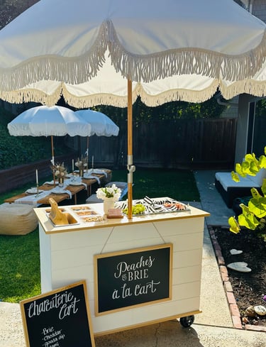 a charcuterie bar cart with umbrella at a party
