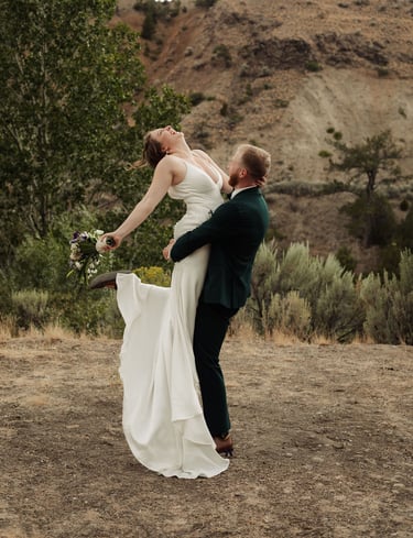 a bride and groom are posing for a photo, groom is holding the bride and spinning