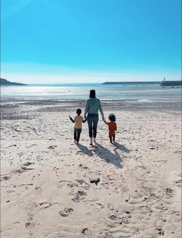 a woman and two children walking on a beach