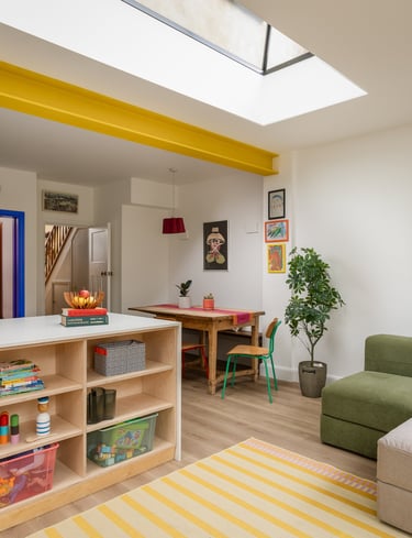 an open plan colourful living room with storage for kids toys, modular sofa and dining table