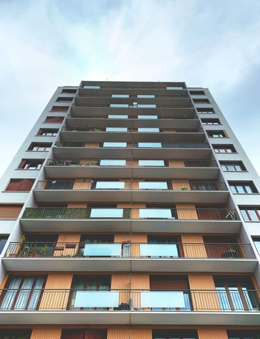 Low angle view of a modern apartment building with glass balconies and wooden facade panels.