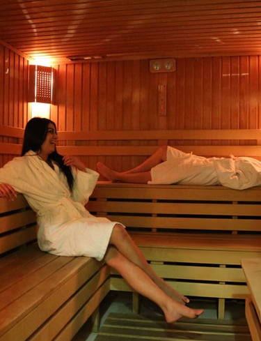 Two women in white robes relaxing and talking inside a warm, wooden luxury massage in hurghada