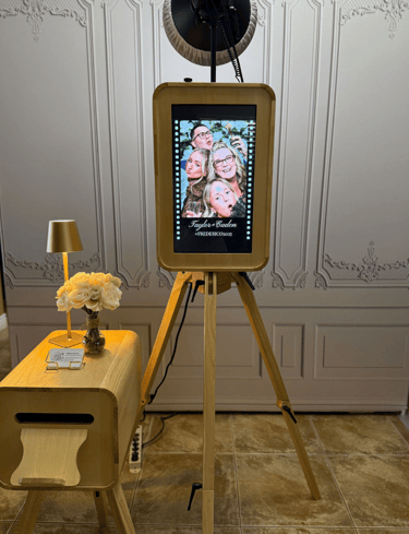 Vintage wood photo booth on a tripod at a wedding event with flowers and a printer.