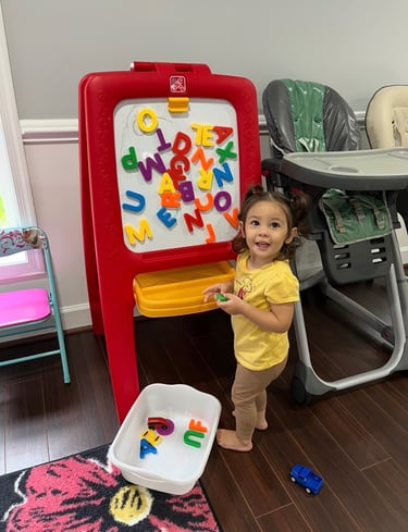 Little girl standing and playing with magnetic letters