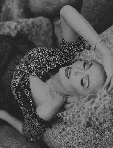 a woman laying on a rock in a black and white photo