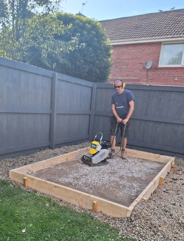 a man compacting a base for a shed
