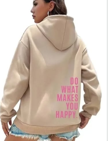 A woman wearing a beige oversized hoodie with pink text that reads Do What Makes You Happy on the back.