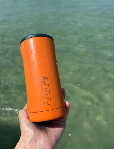 Brandy holding a BrüMate Hopsulator Trio can cooler filled with a drink on a sunny day.