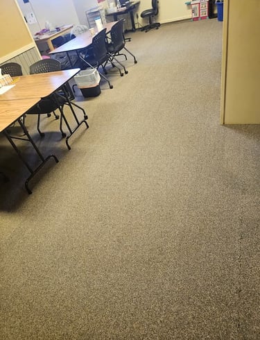 office room with a desks and chairs pushed to the side for the carpets to be cleaned.