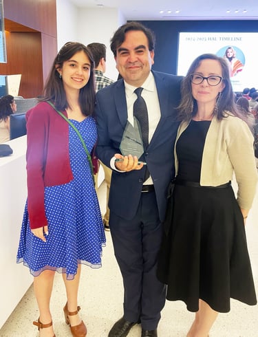 Francisco holds Hispanic Austin Leadership award, smiling with Zoe and Amanda at a celebratory event