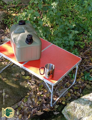 Mesa portátil de camping com o galão de água e a caneca de inox da HW Aventura