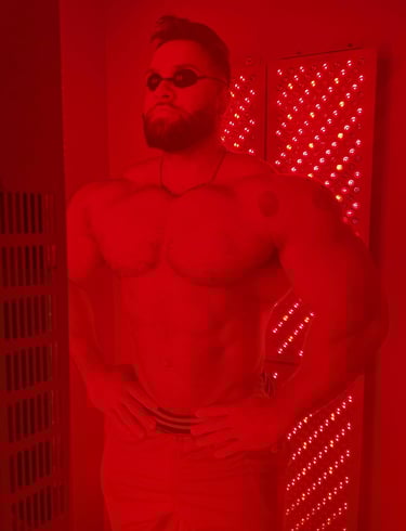 Muscular man using a red light therapy panel for muscle recovery and skin health.