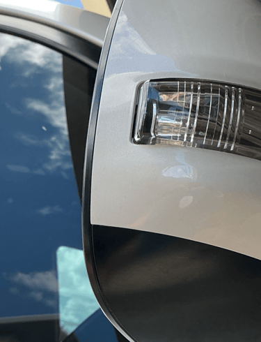 Close-up of a white car side mirror featuring an integrated LED turn signal indicator lamp.