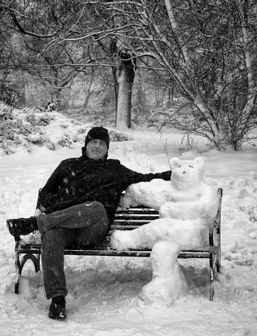 Man sitting on a bench next to a snow bear