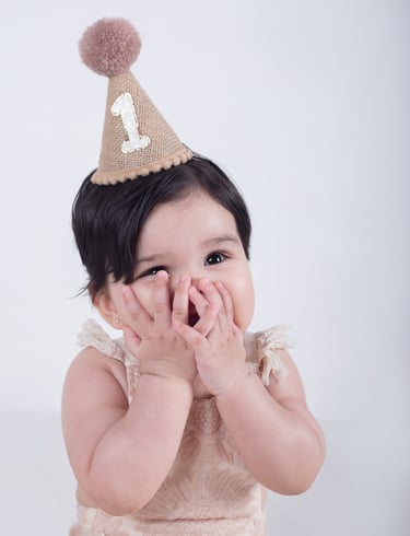 una bebé sonriendo a la cámara con un sombrero de fiesta