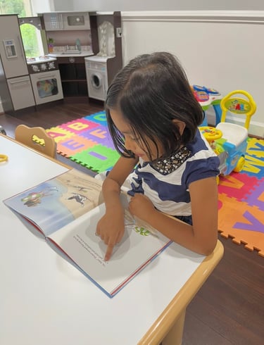Little girl sitting at a table reading a book