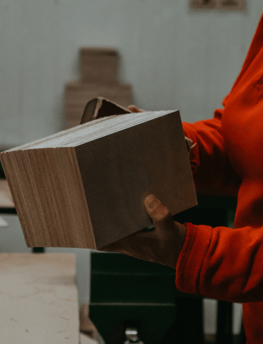 a woman in a red shirt is holding a couple of quality wood pieces