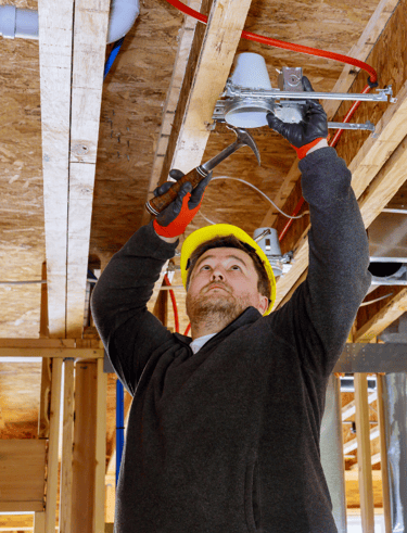 Electrician wearing a hardhat, installing new recessed lights at a business in Early Tx