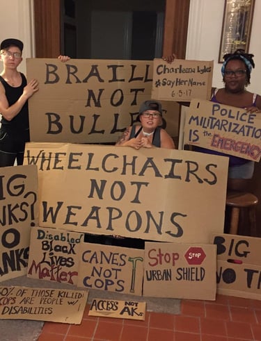 Photo of Stacey with Friends displaying posters they made in protest of Urban Shield and supporting BLM.