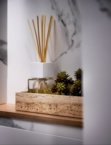 Un jarrón con una planta y un ambientador en un estante.