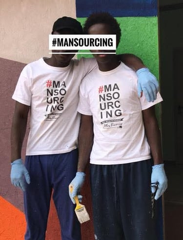 Deux participants du projet Mansourcing posent avec des chemises blanches et des outils de peinture.