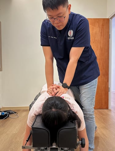 Chiropractor performing manual back adjustment on female patient at Sinisana Chiropractic clinic.