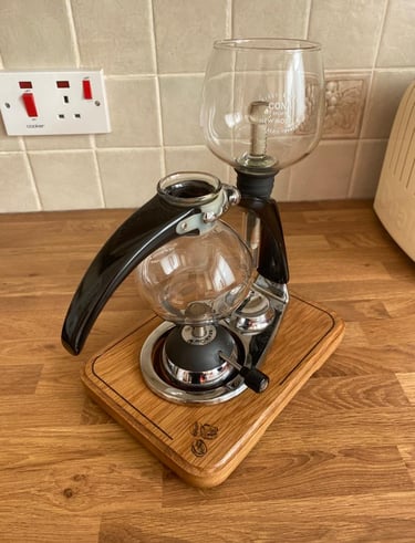 a coffee maker with a glass carafeine on a wooden stand