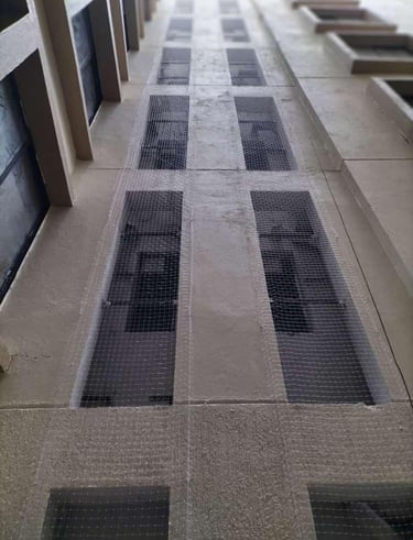 Technician from Arjilli Enterprises securing duct area nets to apartment building.