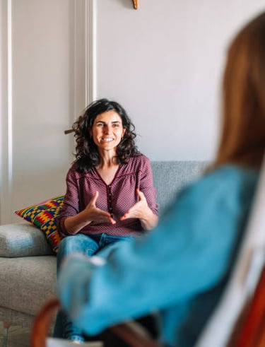 smiling woman with dark hair holding her hands in front of her body is facing person
