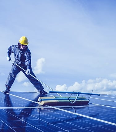 artisan qui nettoies des panneaux sur un toit